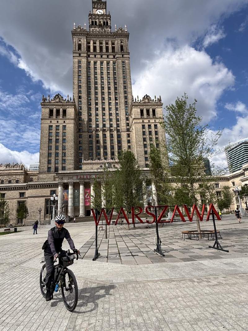 文化科學宮,前面立著 WARSZAWA 的紅色大字,一台單車從廣場騎過。