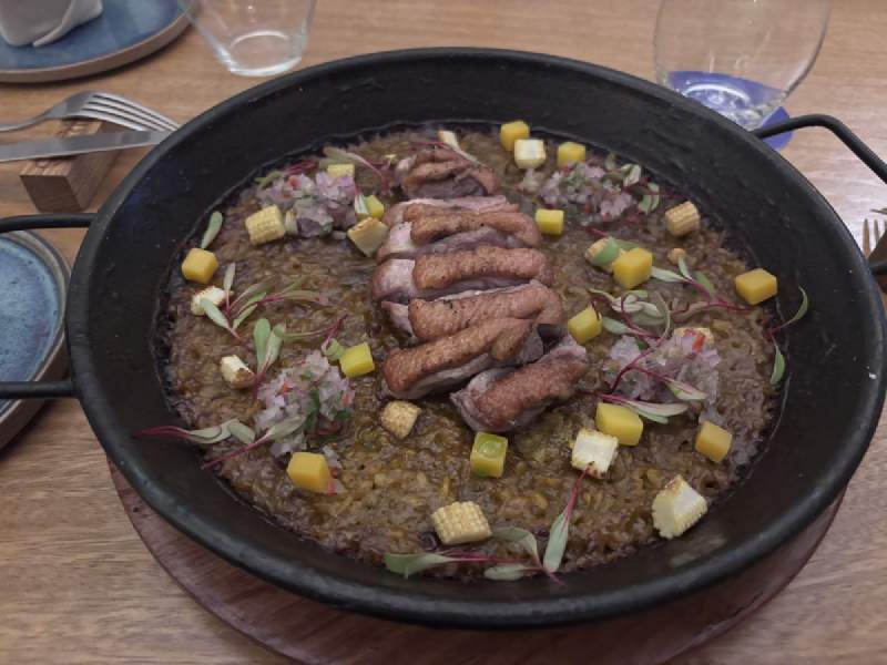 17:27,黑色的鐵鍋裡一份飯,上面放著肉和切塊的水果。