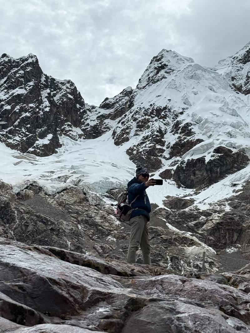 有人站在岩石上,面對雪山和冰。