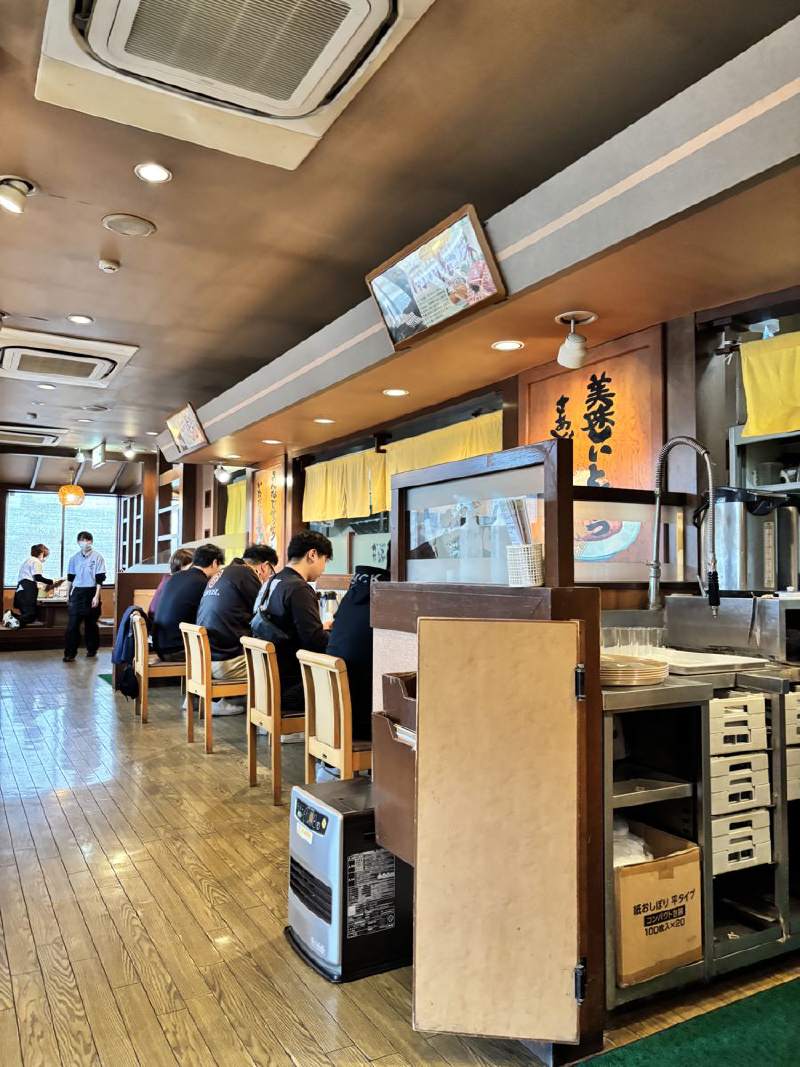 13:22,餐廳裡面,櫃台前坐著幾個人在吃東西。