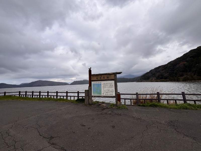 15:08,湖邊空地上立著一塊說明牌,後面是湖和山。
