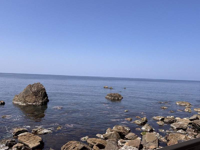 11:45,平靜的海面,礁岩露出水面,天空是漸層的藍。