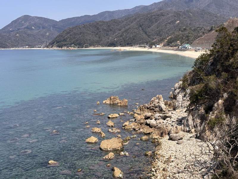 11:56,海灣的海水清透,遠處是沙灘和山。