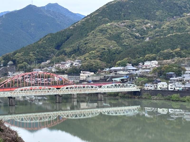 10:13,從新宮城跡看熊野川:紅色拱橋和白色桁架橋並排,倒影在河上。對岸已經是三重縣。
