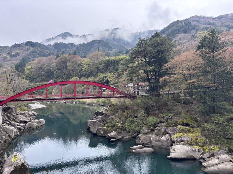 10:43,木曾の桟一帶的木曾川:紅色拱橋、河裡一顆一顆的大石頭,水面映著山,山頭的雲還沒散。
