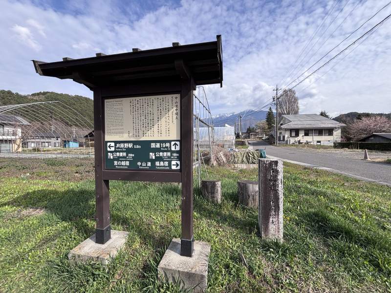 15:30,原野站附近的「中山道中間點」,旁邊一根石柱刻著「中山道 中間地點」;牌子後面,露出頂上積雪的山。