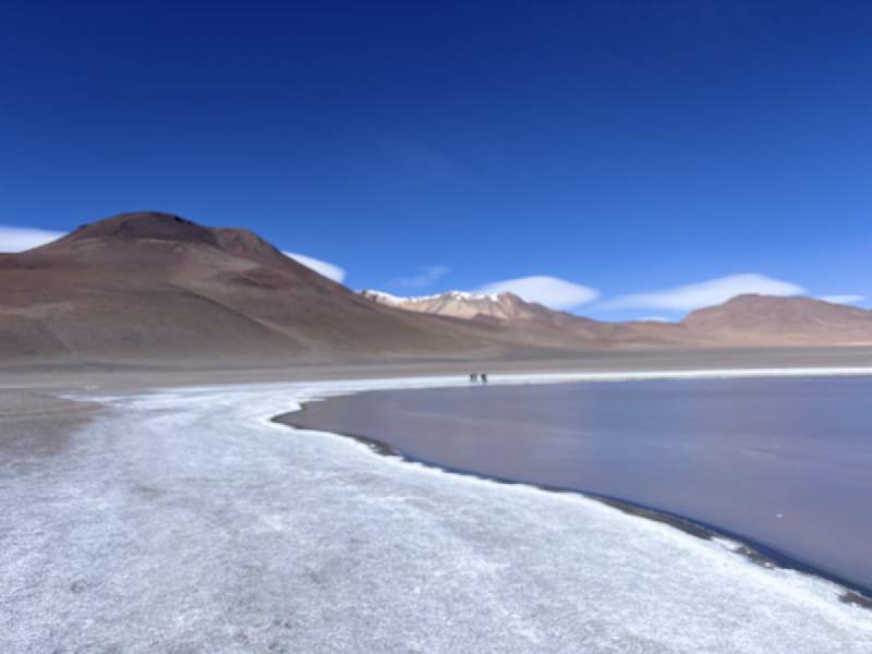 14:34,白色的湖岸彎進湖裡,遠處山上有雪。
